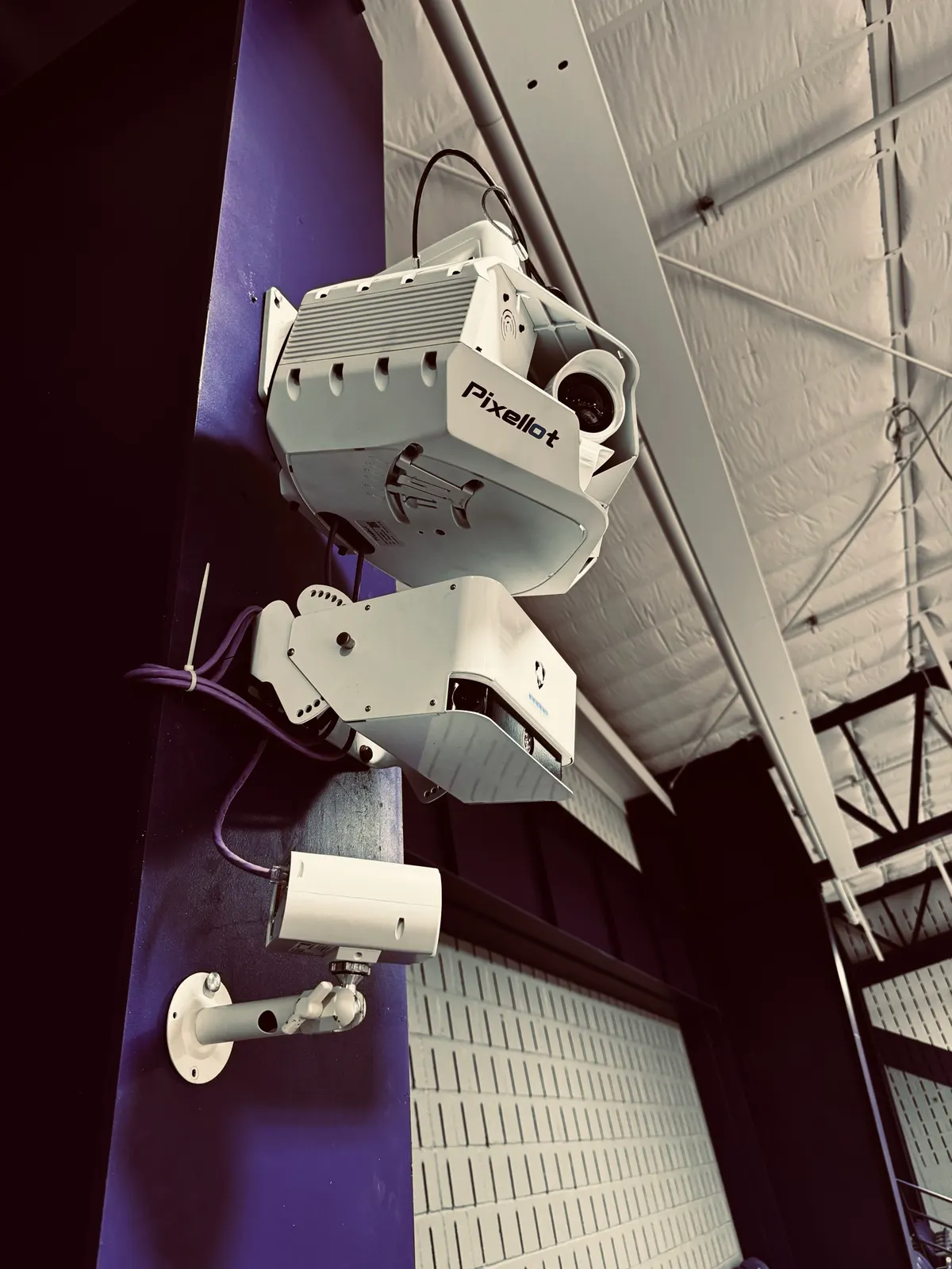 Pixellot camera unit mounted high on a gymnasium wall